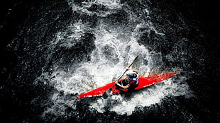 top-angle photograph of person riding red sit-in kayak