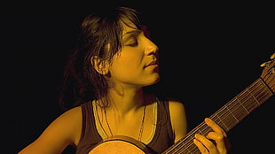 woman wearing black tank top playing classical guitar