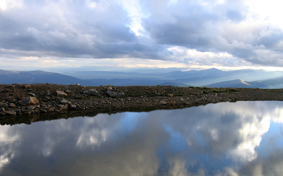 landscape photography of a lake near black stone field HD wallpaper