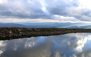 landscape photography of a lake near black stone field