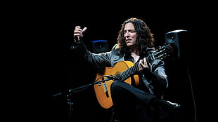 man wearing black top playing guitar on stage