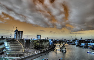 wide photography of city near river under nimbus clouds, tower bridge