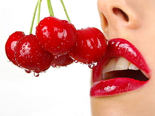 five red cherries on human's red lips