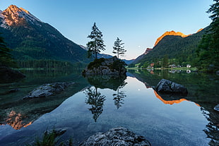 photo of body of water surrounded with green trees and mountains