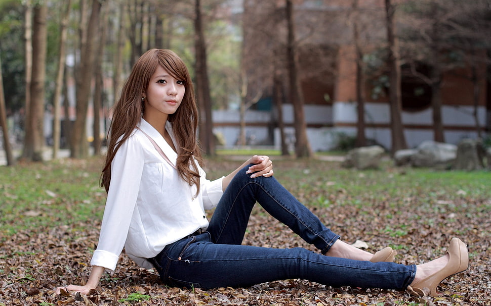 woman wearing white button-up long-sleeved blouse, blue denim jeans, with pair of platform heeled shoes sitting on green grass with dried leaves during daytime HD wallpaper