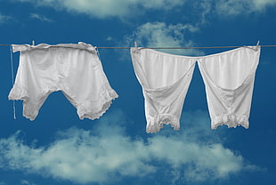 two white shorts hanging on wire