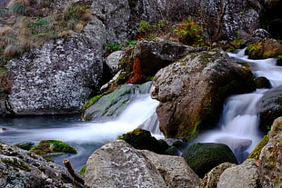 water falls surrounding by stones during day time