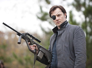 man wearing black zip-up jacket holding gun
