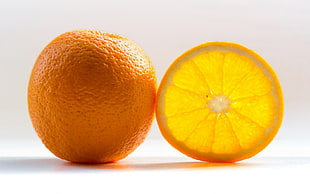 orange with orange slice on top of white surface
