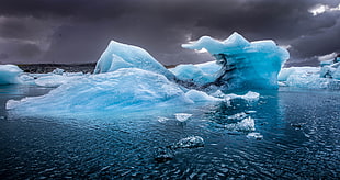 ice bergs on ocean under gray clouds