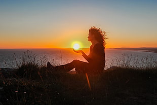 woman sitting on cliff during sunset