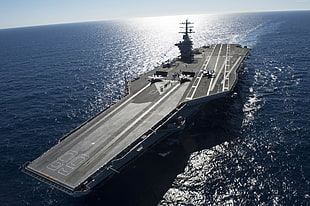 black aircraft carrier on body of water during daytime