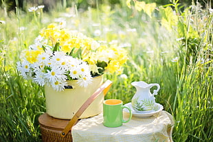 white and yellow petaled flower in vase beside wash basin and pitcher set and green ceramic mug