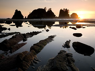white body of water with rock formation during sunset