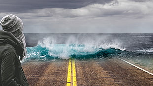 woman standing looking at sea waves hitting concrete road