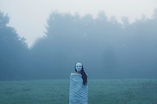 person standing in front of green grasses during fog