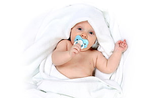 baby with blue pacifier lying on white blanket