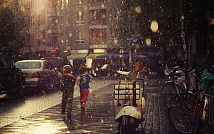 two boy walking on sidewalk during rainy day