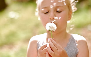selective focus photography of girl holding dandelion