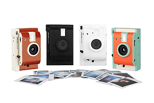 four assorted-color instant cameras with photos