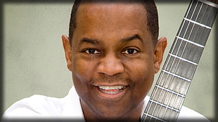man wearing white shirt holding guitar