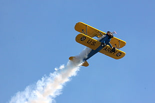 yellow and teal U.S. Army biplane with contrail at the air, aircraft, biplane, Boeing Stearman, vehicle