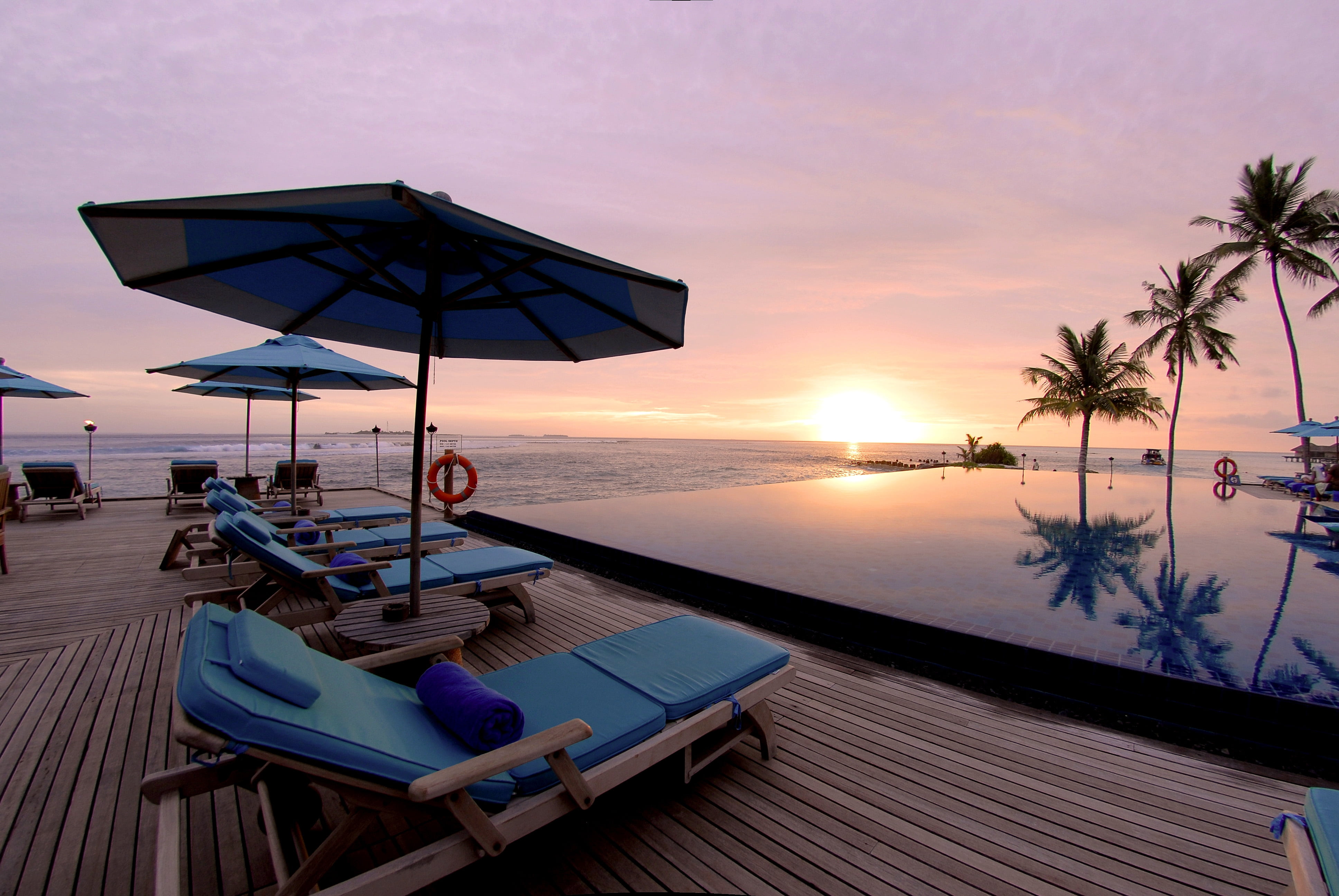 blue and white beach lounge chairs on wooden dock during sunset