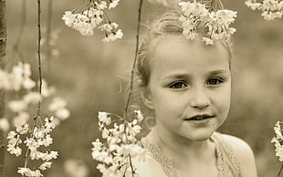 sephia photography of girl behind flowers
