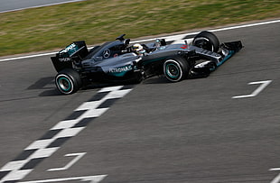 silver and black Mercedes-Benz Petronas F1 racing car crossing the finish line
