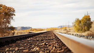 low-angle view selective focus photo of brown metal train tracks, railway, depth of field, stones, worm's eye view HD wallpaper