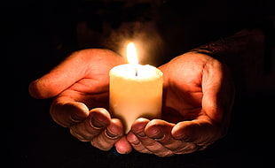 person holding a white candle  in the dark