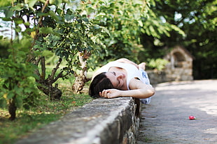 shallow focus photography of woman lying beside green plants