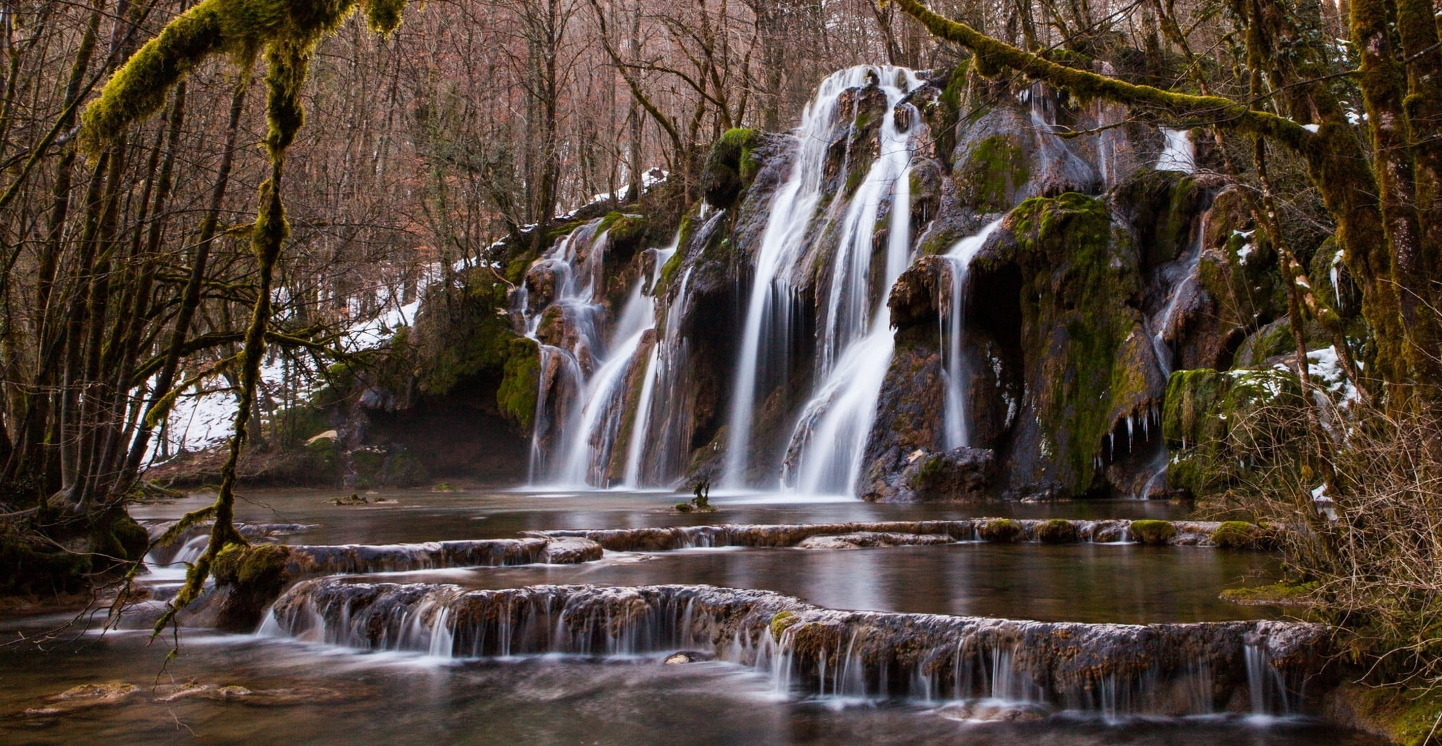 timelapse photo of moss-covered rocks with waterfall