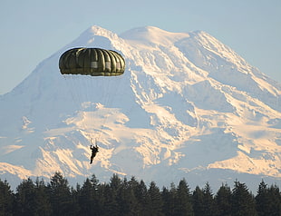 person holding parachute about to land with snow filled mountain background