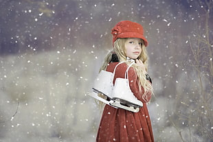 selective focus photography of girl wearing red dress carrying ice skates