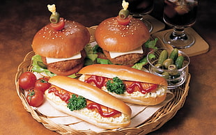 two hamburgers and two hotdogs on brown wicker platter