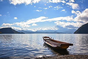 brown boat on body of water near mountain during daytime HD wallpaper