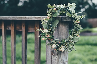 green and white floral wreath on brown wooden railing