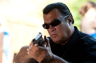 man wearing sunglasses holding pistol