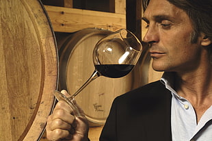 man holding wine glass beside brown wooden board