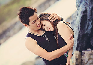 man hugging woman beside stone HD wallpaper