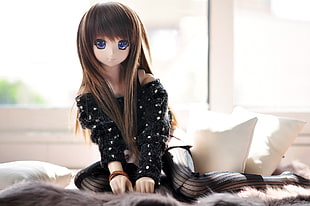 black dressed Anime doll on bed near two throw pillows