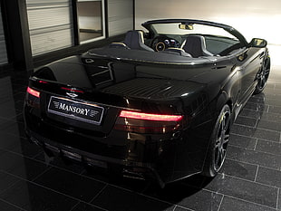 black Aston Martin Mansory convertible coupe parked on black tiled floor