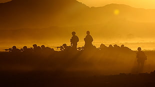 silhouette of soldiers holding rifles during sunrise