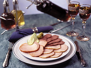 brown ham on white ceramic plate on gray wooden table