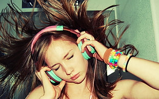 woman using pink and teal corded headphones