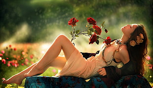 woman lying on blue surface with red flowers on knee