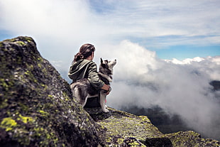 woman with dog on top of The mountain during day time