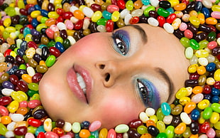 woman's face surrounded with assorted-color jelly beans
