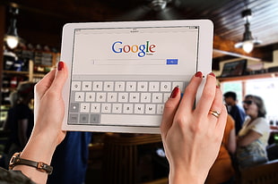 person holding white iPad browsing google